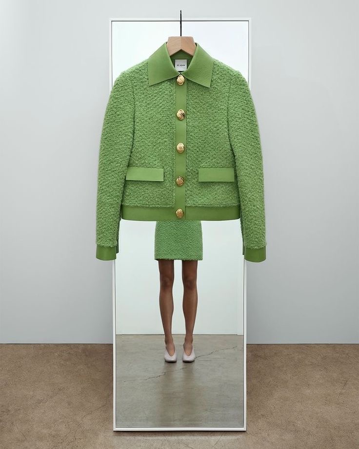 Veste verte sur cintre devant un miroir